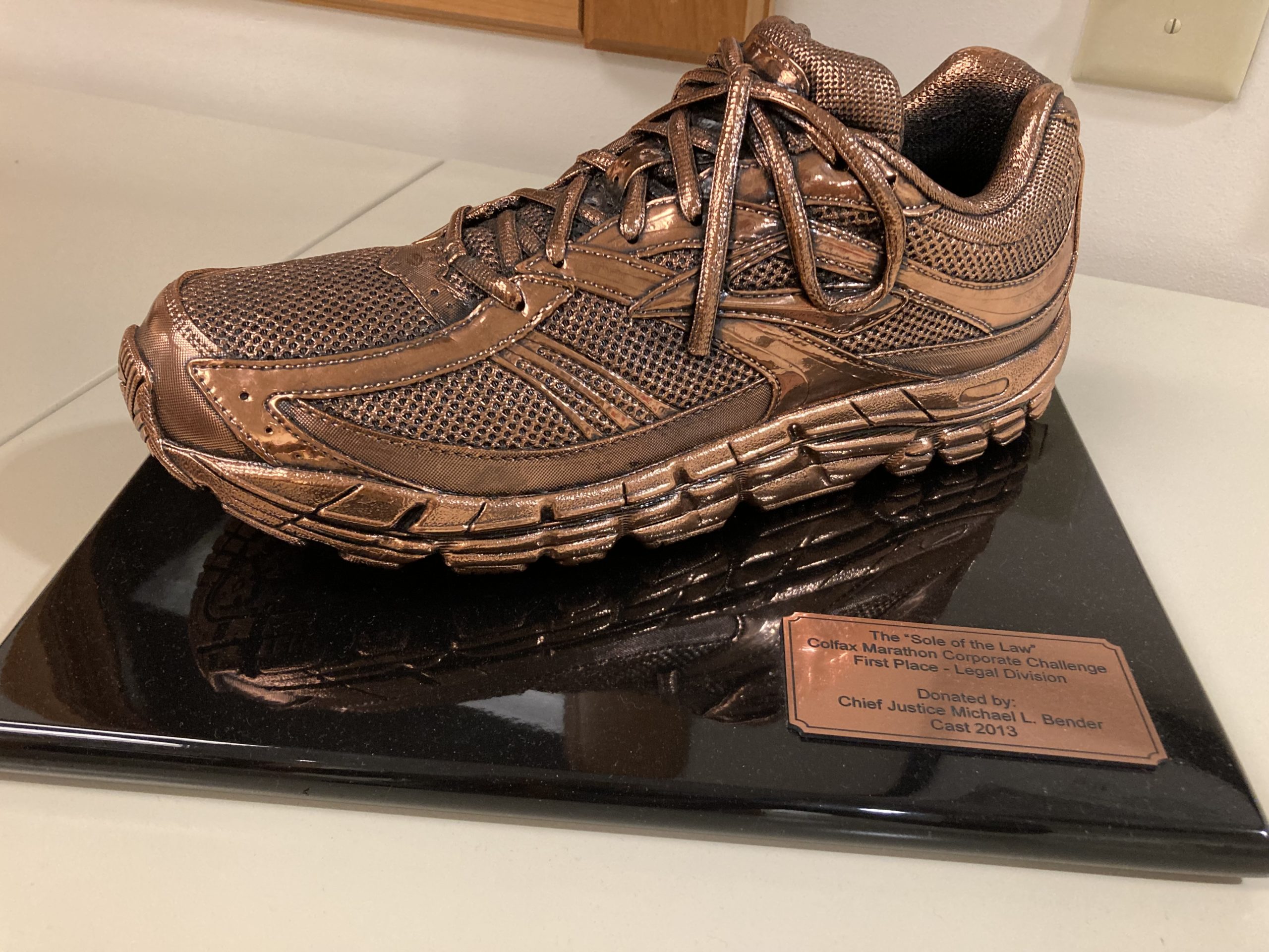 a massive bronzed running shoe sits on a plaque as part of a trophy for the winner of the legal division of the Colfax Marathon.