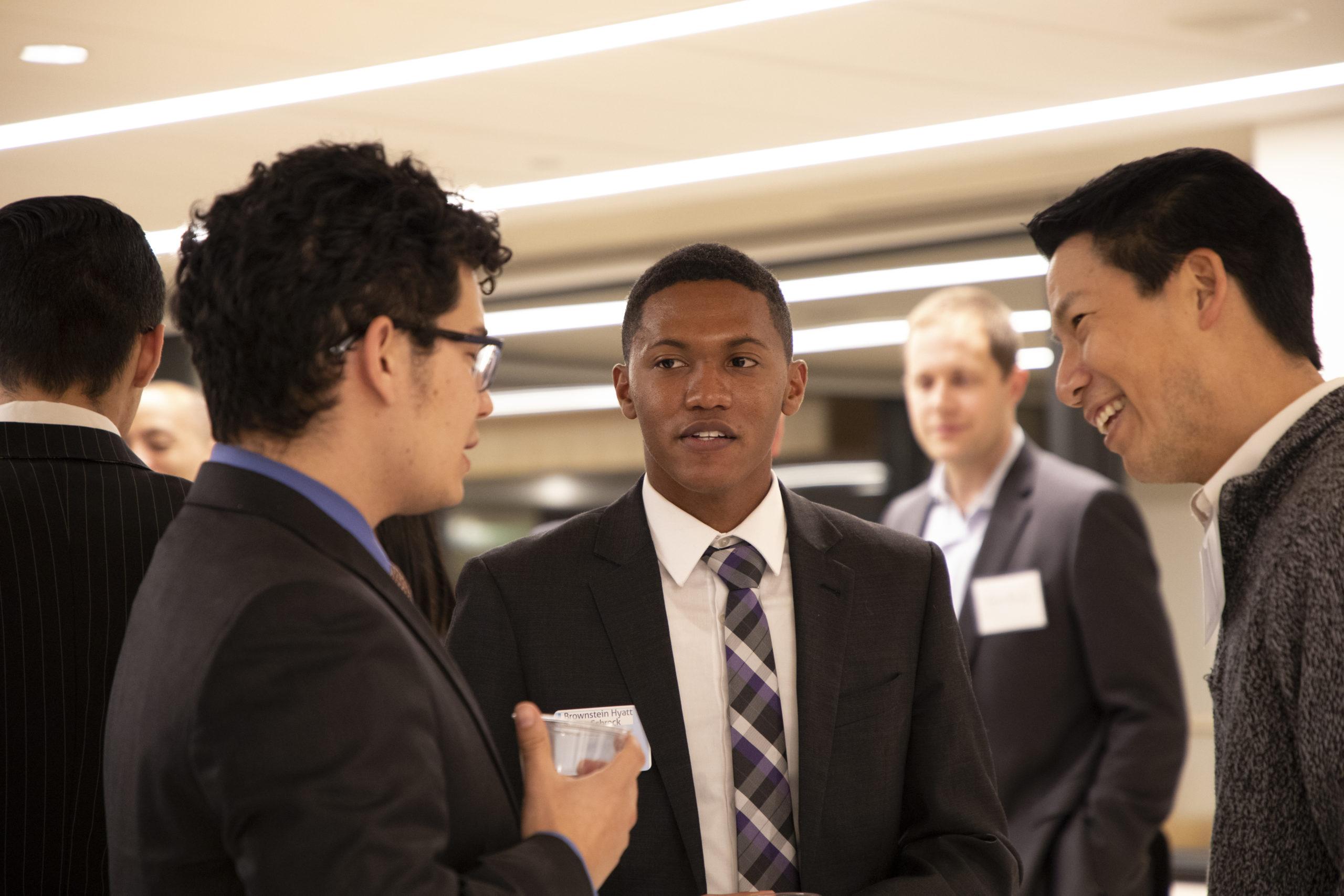 Three men in suits socializing with each other at an event