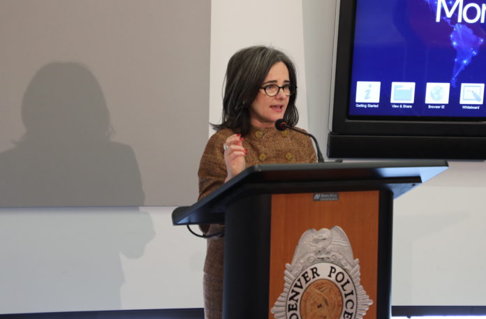 A lady in a brown dress standing behind a podium speaking