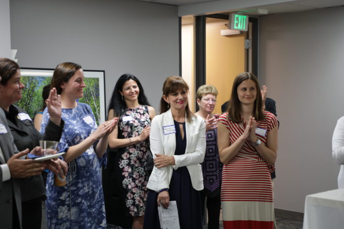 five women clapping around a woman being recognized for an accomplishment