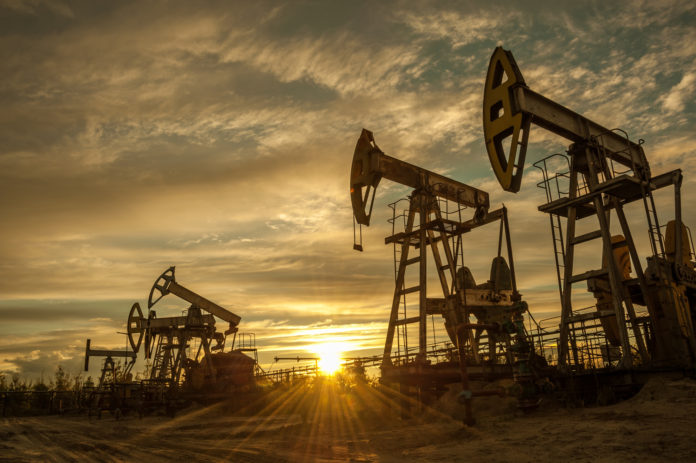 Oil pump jacks at sunset sky background. Toned.