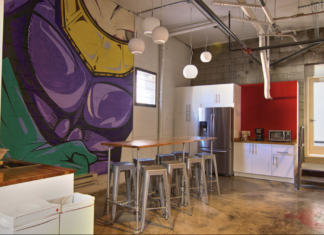 Learning To Share The inside of an office that is very casual with a purple and yellow mural on the wall