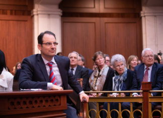 Colorado AG Intervenes in Health Care Merger Attorney General Phil Weiser sitting at a table in a court room
