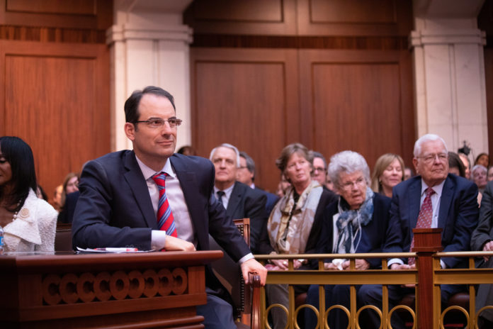 Attorney General Phil Weiser sitting at a table in a court room