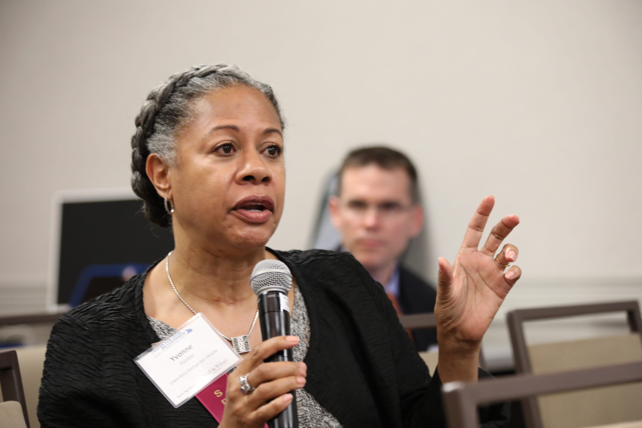 A close up of a woman with a microphone in her hand speaking in an animated way