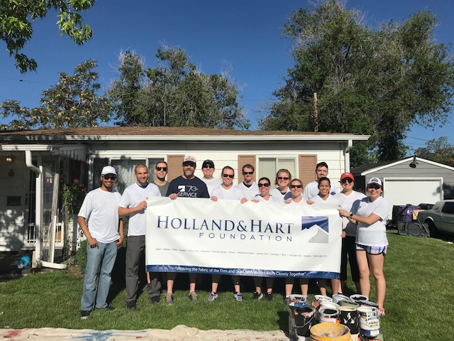 A group of people holding up a large sign that says Holland and Hart