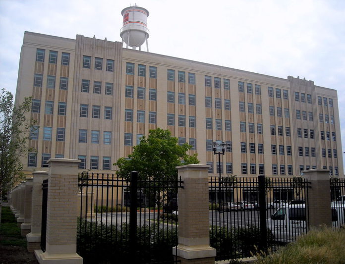 A large rectangular service warehouse surrounded by black metal fencing