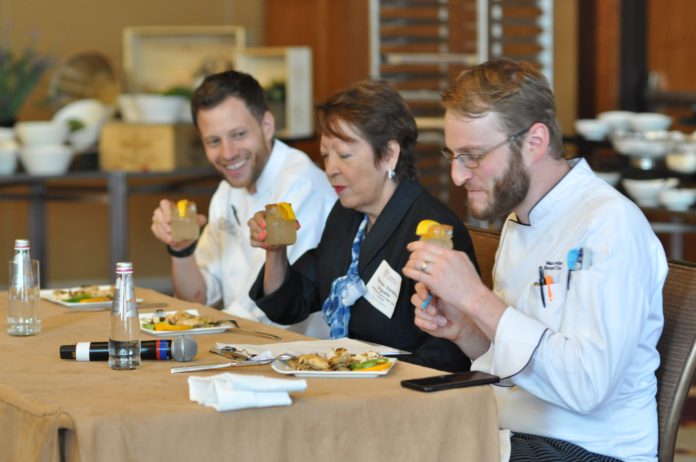 Three people sitting at a table judging food and cocktails