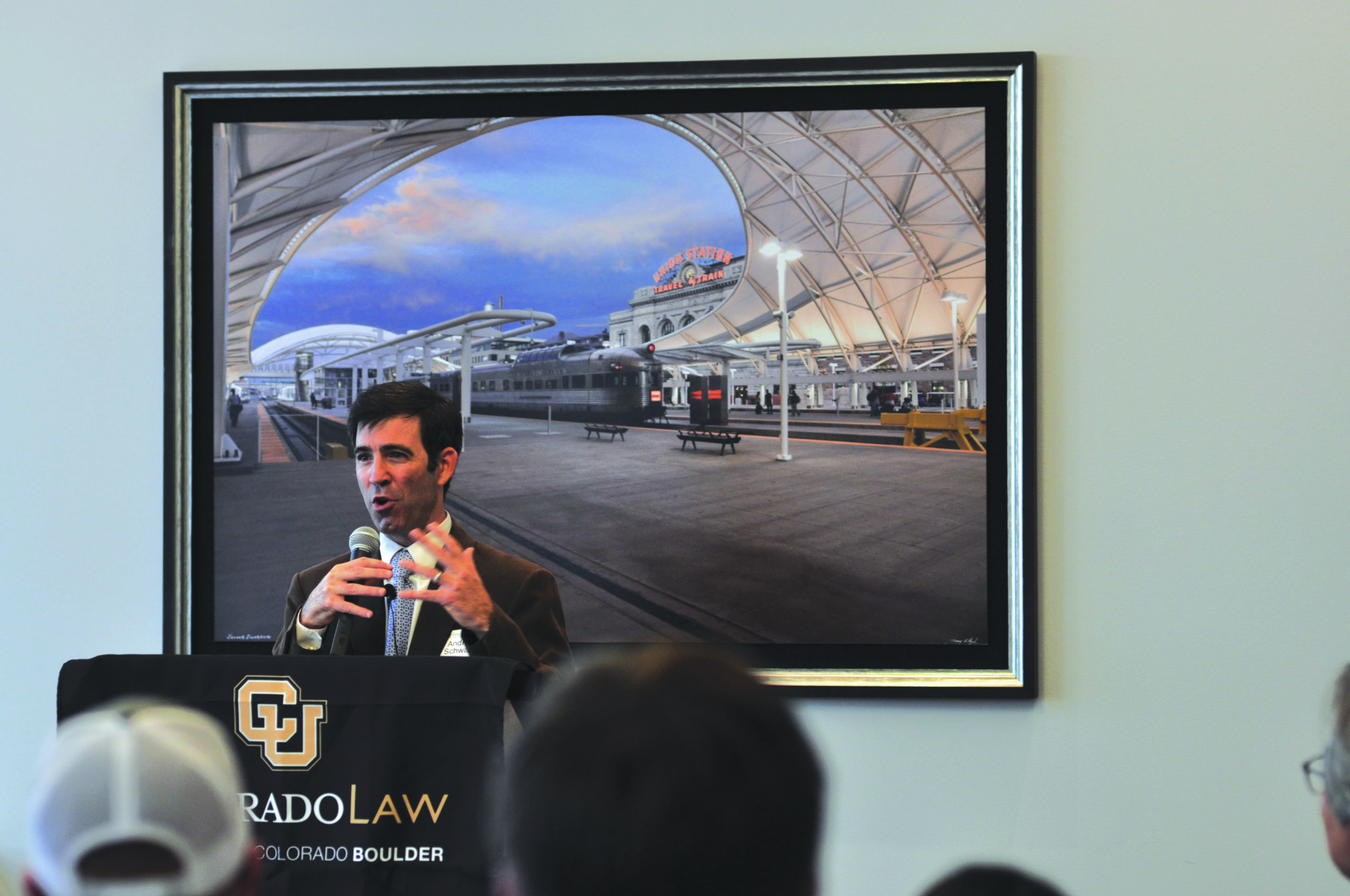 Restorative Justice Program Launches in Denver A man in a suit speaking at a crowdfunding event in front of a large photo of a train station