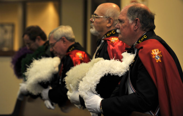 Knights of Columbus in their uniforms bowing their heads