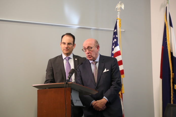 Colorado Attorney General Weiser and attorney Kenneth Feinberg at a podium announcing a compensation program for people who suffered sexual abuse by Colorado Catholic priests as children.