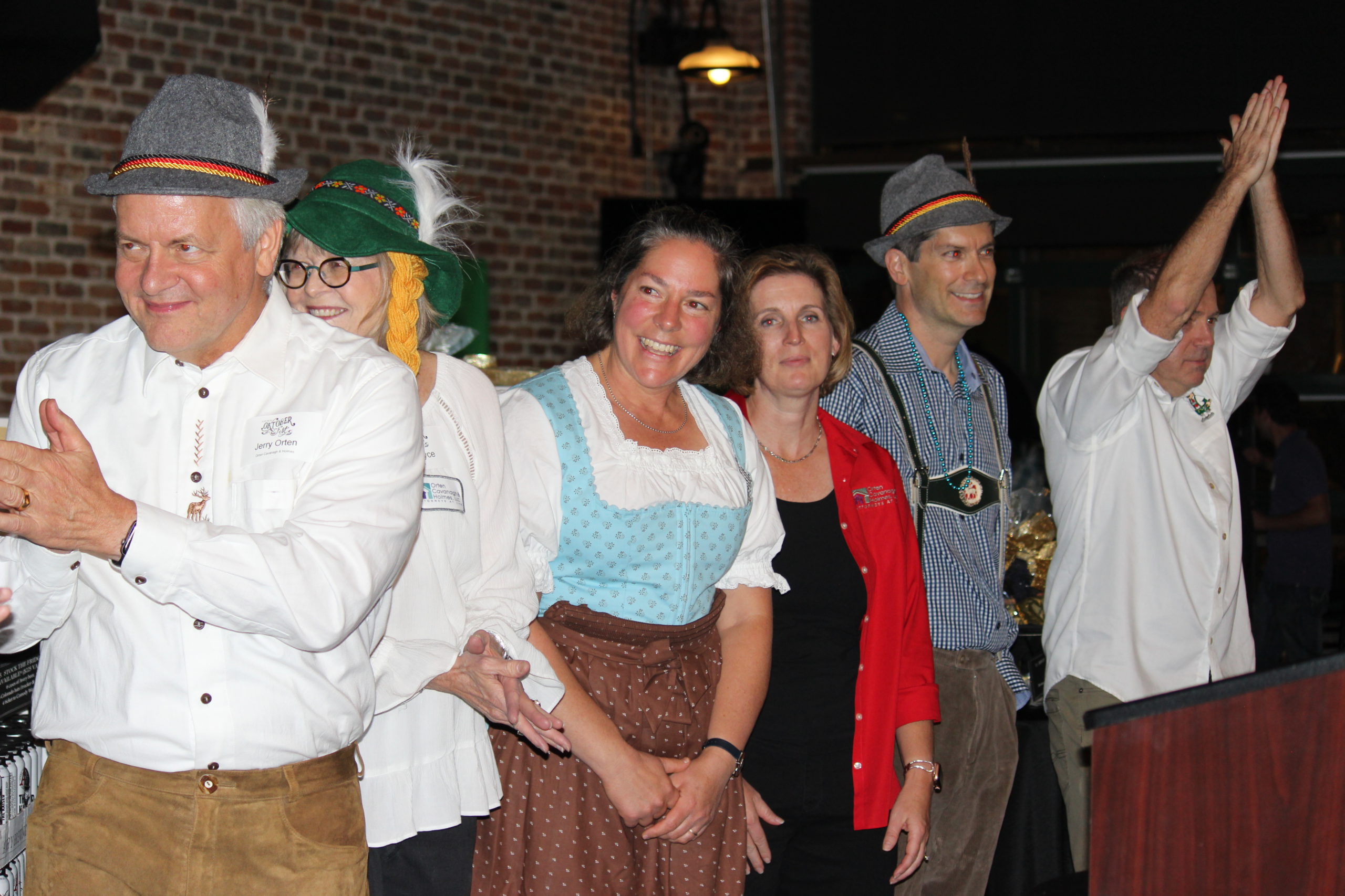 A group of people wearing German inspired clothes in a line smiling and cheering A group of people wearing German inspired clothes in a line smiling and cheering