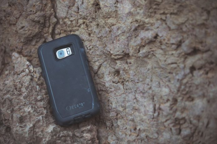 A black smart phone face down on a rock