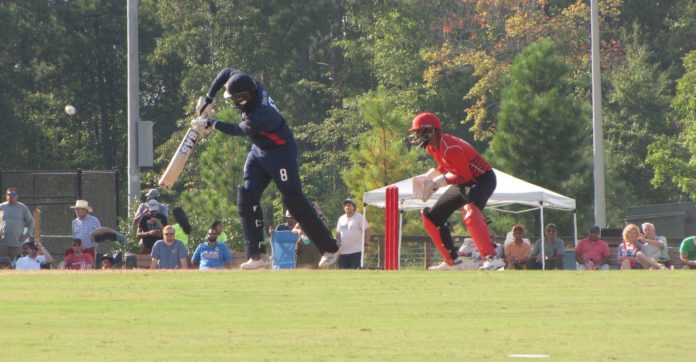 Two cricket players, one in blue and one in red playing against eachother Two cricket players, one in blue and one in red playing against eachother