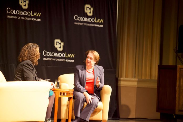 Two women sitting on a stage during an interview stage in a university auditorium
