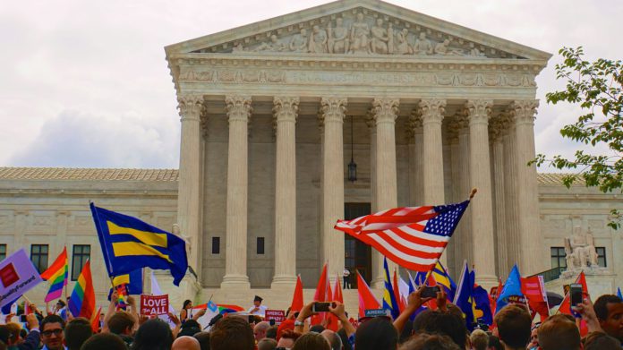 large crowd of people in front of the united states supreme court waving American and equal rights flags