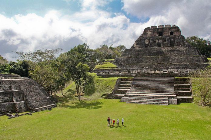 An ancient aztec temple made of stone in a green field