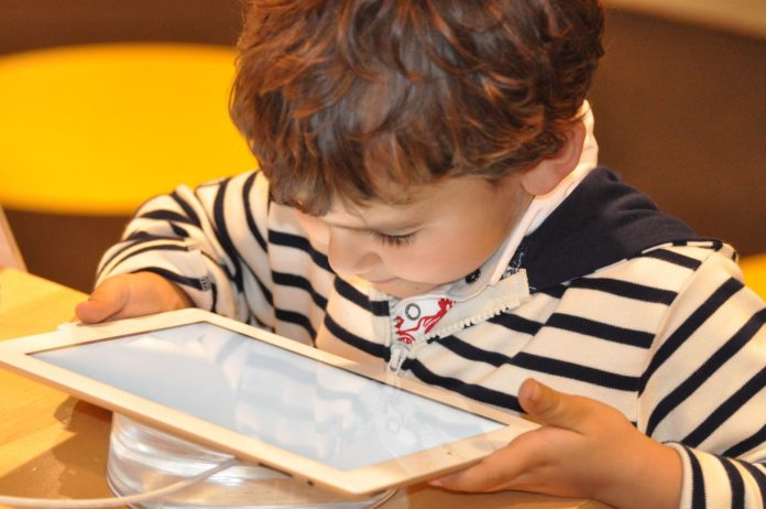 A young child in a striped shirt looking at an i pad