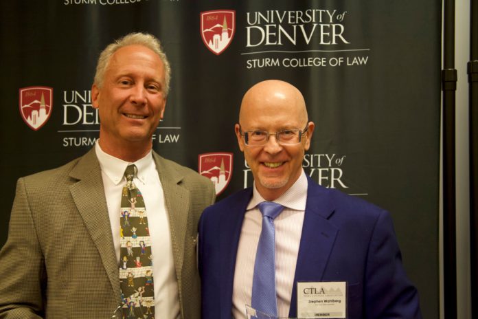 Two men in suits standing next to each other smiling