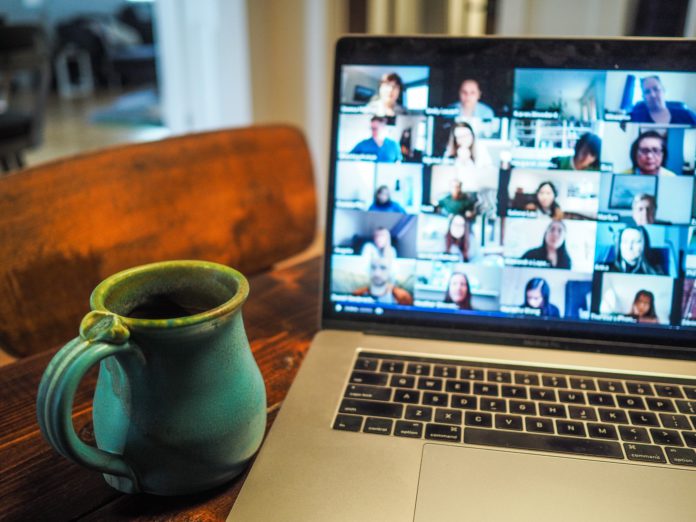 A full coffee mug sits near a laptop on a video conference call.