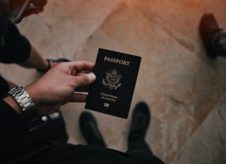 10th Circuit Says Passport Revocation for Unpaid Taxes is Constitutional Someone looks down at a passport they're holding nearby a set of luggage.