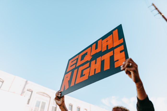 A protestor holds a sign high that reads 