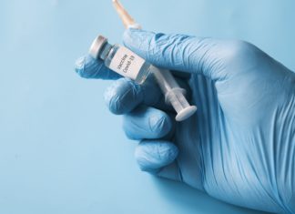 Employers Increasingly Open to Vaccine Mandates, Survey Says A gloved hand holds a vaccine and needle.