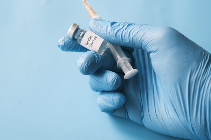 towfiqu-barbhuiya-j1dzPFts4GU-unsplash A gloved hand holds a vaccine and needle.
