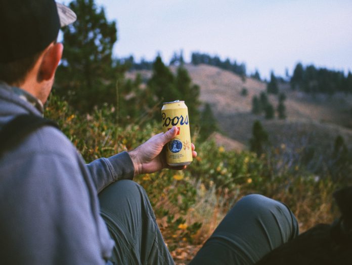 A hiker looks down at a Coors beer can.