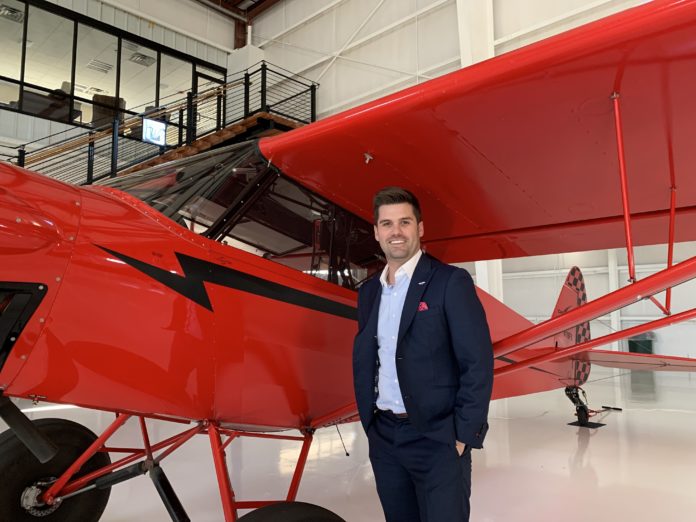 Joe LoRusso stands next to a small red plane in a hangar in Broomfield, Colorado.