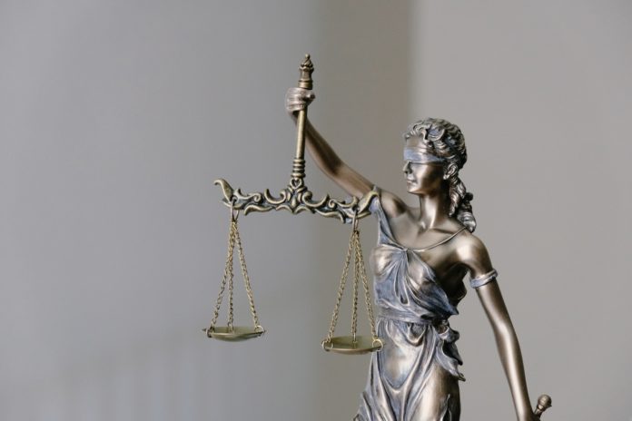 a blindfolded lady justice statue upholds bronzed scales while a sword rests at her side in her other hand