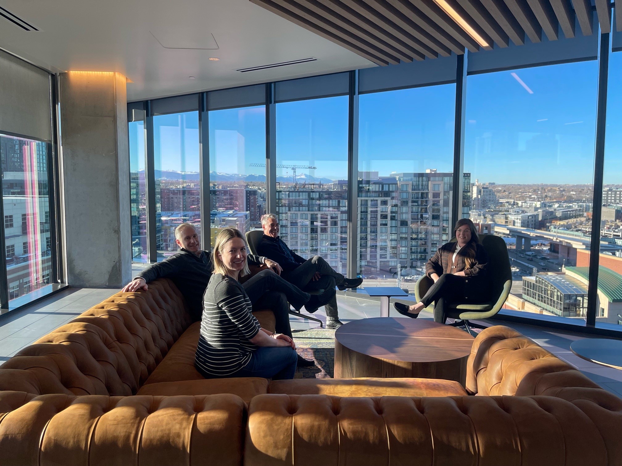 A group of Lewis Roca Denver employees gather around a seating area in the new McGregor Square office