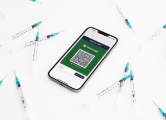 ‘Natural Immunity’ Bill Dies in Committee A phone displaying a digital vaccine card surrounded by syringes.