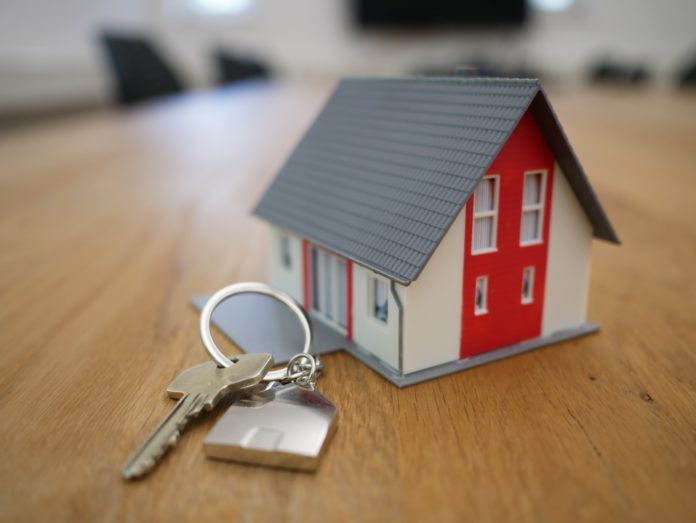 a tiny model of a house sits on a desk next to a set of house keys