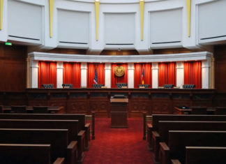 Colorado Supreme Court Weighs in on Murky Statutory Settlement Interest Rates The Colorado Supreme Court room. A courtroom with seven seats and red textiles in front of a podium with benches