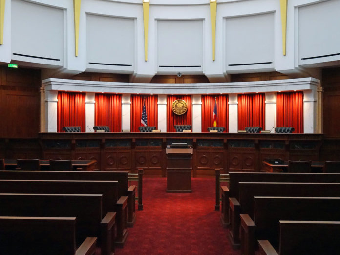 The Colorado Supreme Court room. A courtroom with seven seats and red textiles in front of a podium with benches