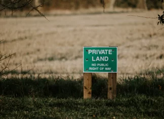 Corner Crossing is a Legal Gray Area in Colorado and Many Western States A green sign that reads “Private Land No Right of Way” with bullet holes in it in front of an open field.