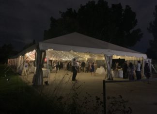 Colorado Hispanic Bar Association Honors Member Impact at Annual Banquet A white tent lit up at night by string lights in a garden. The silhouettes of people in dresses and suits are inside.