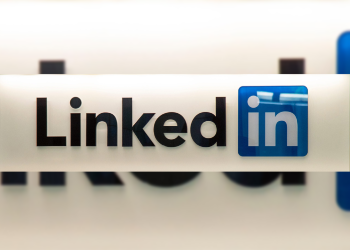 LinkedIn name spelled out with “Linked” spelled in black and “In” spelled in blue. Behind it is a cream colored background.