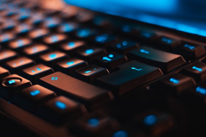 A closeup of a black keyboard with the keys lit up blue.