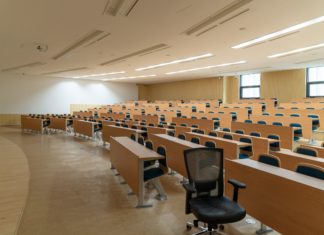 U.S. Supreme Court to Hear Oral Arguments on College Admission Issues Oct. 31 A large classroom is filled with rows of tables with chairs in front of them. After each row, the brown tables and chairs become more elevated.