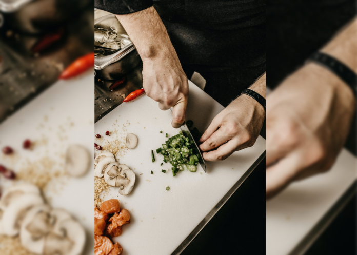 Someone cutting green vegetables on a white cutting board. Cut up mushrooms and meat can also be seen.