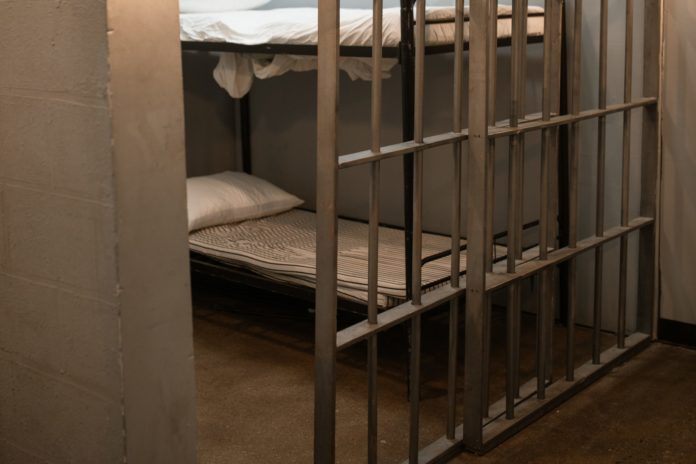 pexels-rodnae-productions-6064890-scaled A jail cell is glimpsed through a slightly open cell door