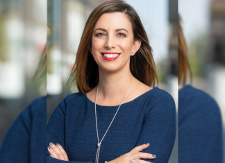 The Ins and Outs of Interior Design Law A woman wearing a blue top and necklace stands smiling with what appears to be a building behind her.