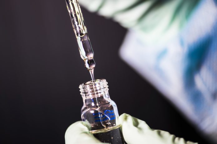 a laboratory technician is in the process of pipetting a sample of vitamin E acetate.