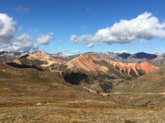 Mountains tower over San Juan County in Colorado, a blue sky above is dotted with light clouds