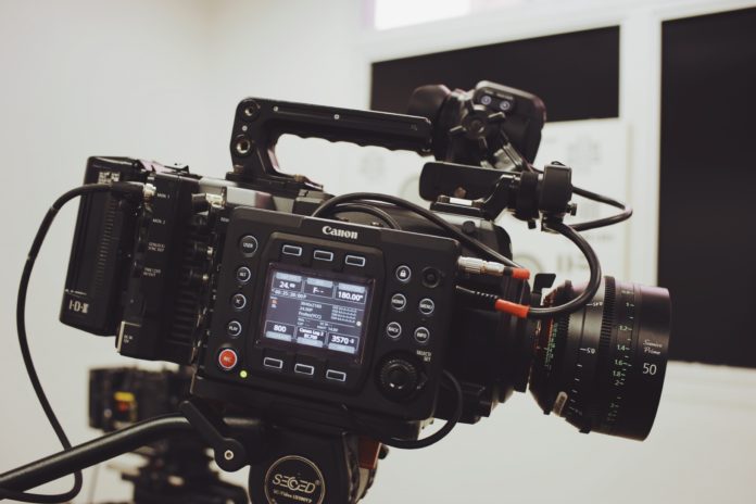 pexels-bruno-massao-3028442 An image of a black video camera with a screen on the camera showing different numbers. Cords are connected all over the camera.