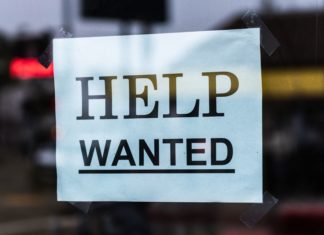 Hiring and Retention: How Firms Are Keeping Attorneys A help wanted sign is posted with black lettering on white paper.