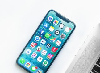 10 Years Later: NAMI Colorado Law Line An iPhone is next to a computer keyboard. Multiple apps can be seen on the phone which has a blue background.