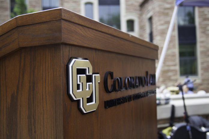 A wood podium sits outside with the “CU” logo and reads in black “Colorado Law.”